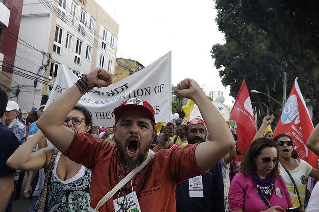 Ativista erque os braços e grita, com energia, na marcha do FSM 2018
